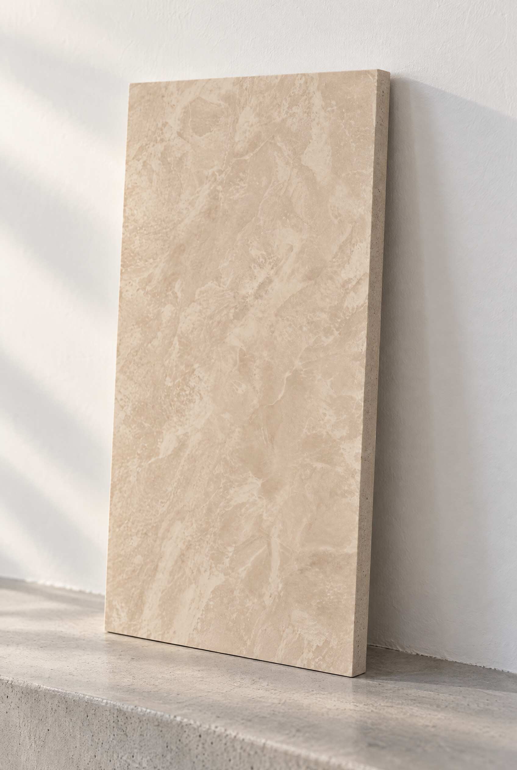 Illustration of a honed marble tile in Akhisar Beige, leaning against a white wall on a concrete step.