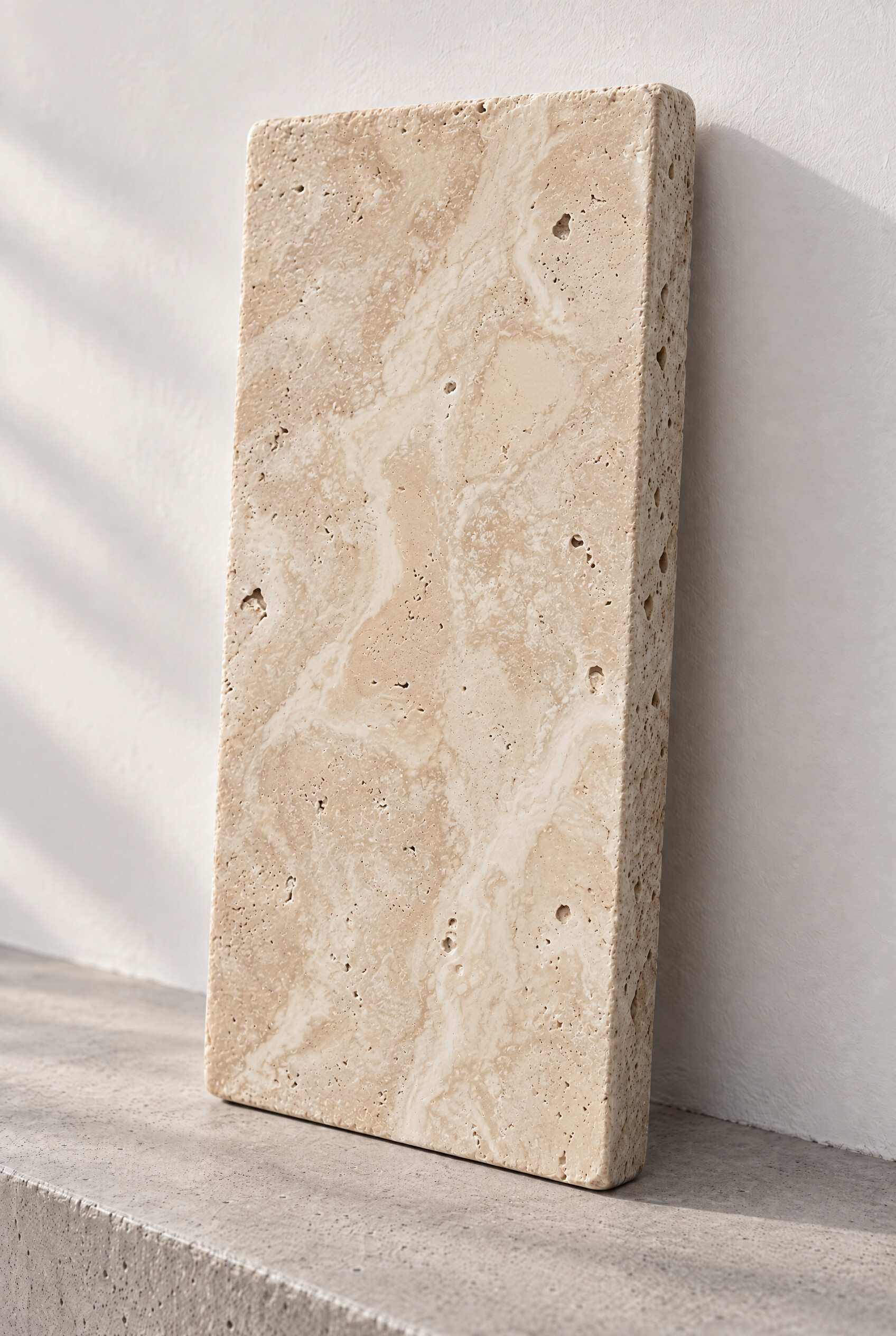 Illustration of a tumbled travertine paver in Classic, leaning against a white wall on a concrete step.