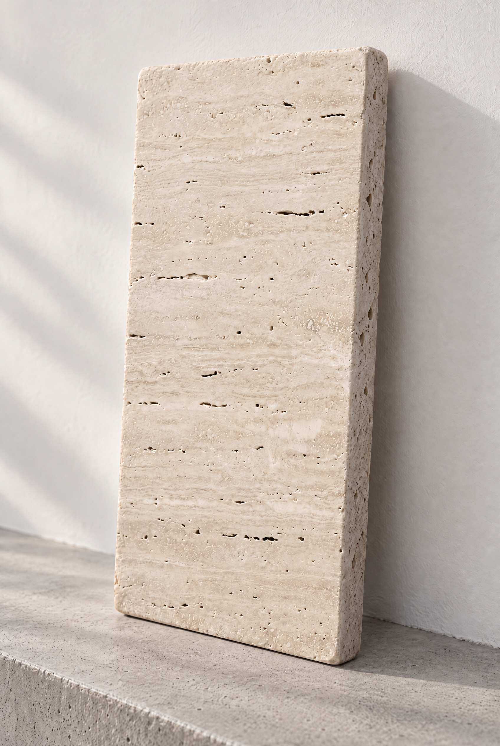 Illustration of a tumbled travertine paver in Ivory, leaning against a white wall on a concrete step.
